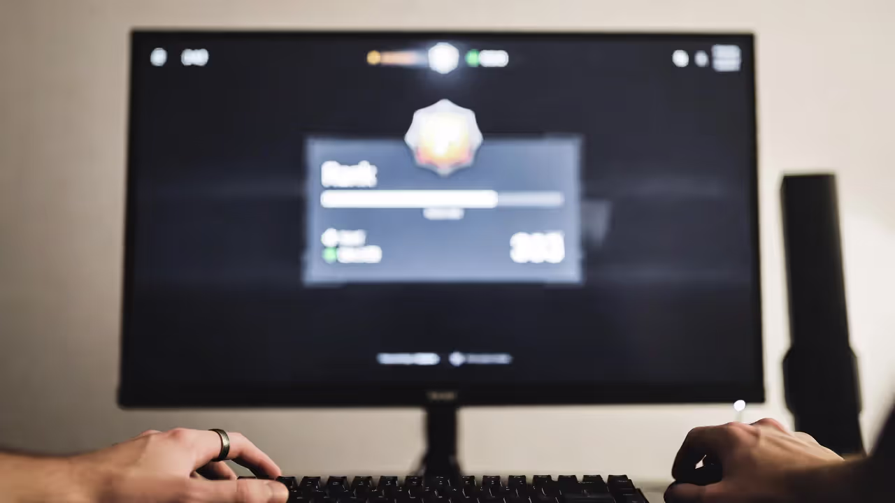 Blurred rank-up screen on a monitor with hands on mouse and keyboard