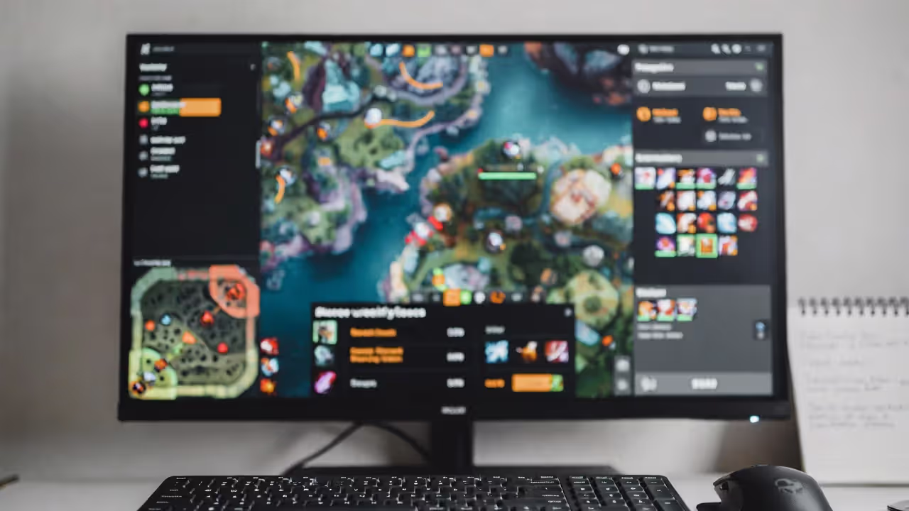 Blurred MOBA map interface on a screen with a notebook of strategy notes and gaming mouse and keyboard.