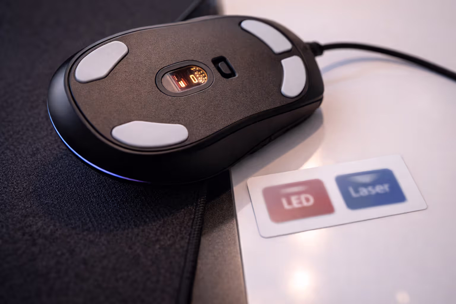 Close-up of a mouse sensor and feet illustrating optical vs laser tracking surfaces